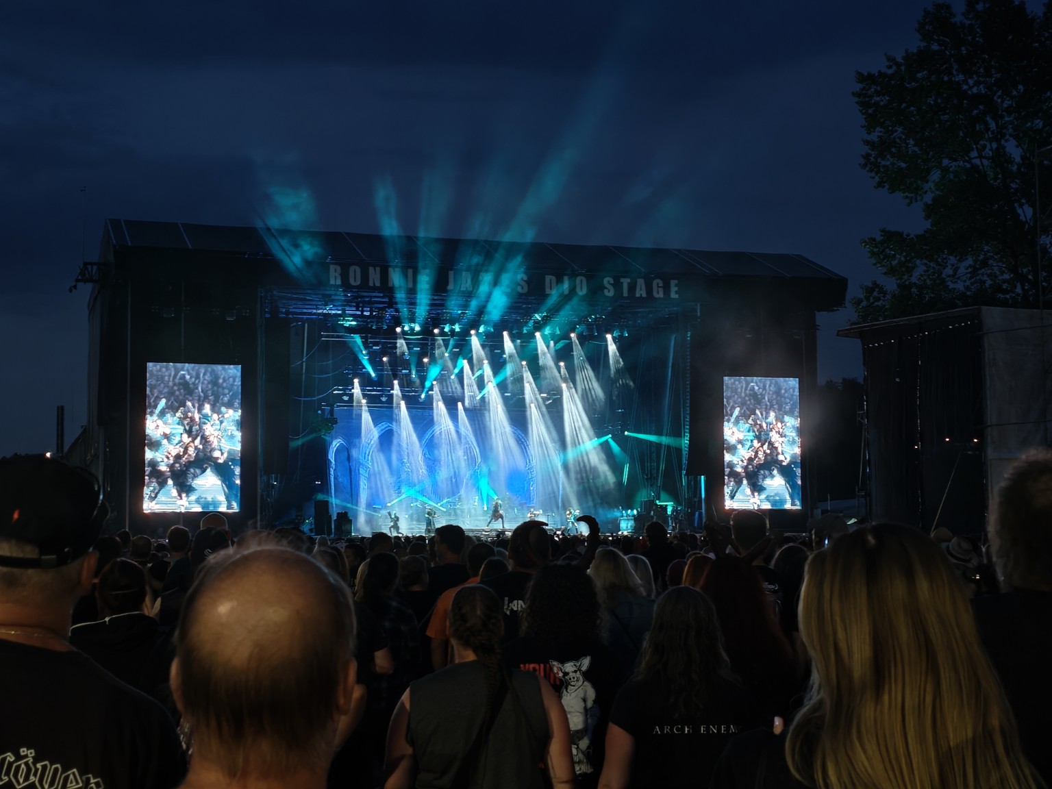 Moje fotografie z Masters of Rock 2026: večerní pódium s modrými světly a publikem.